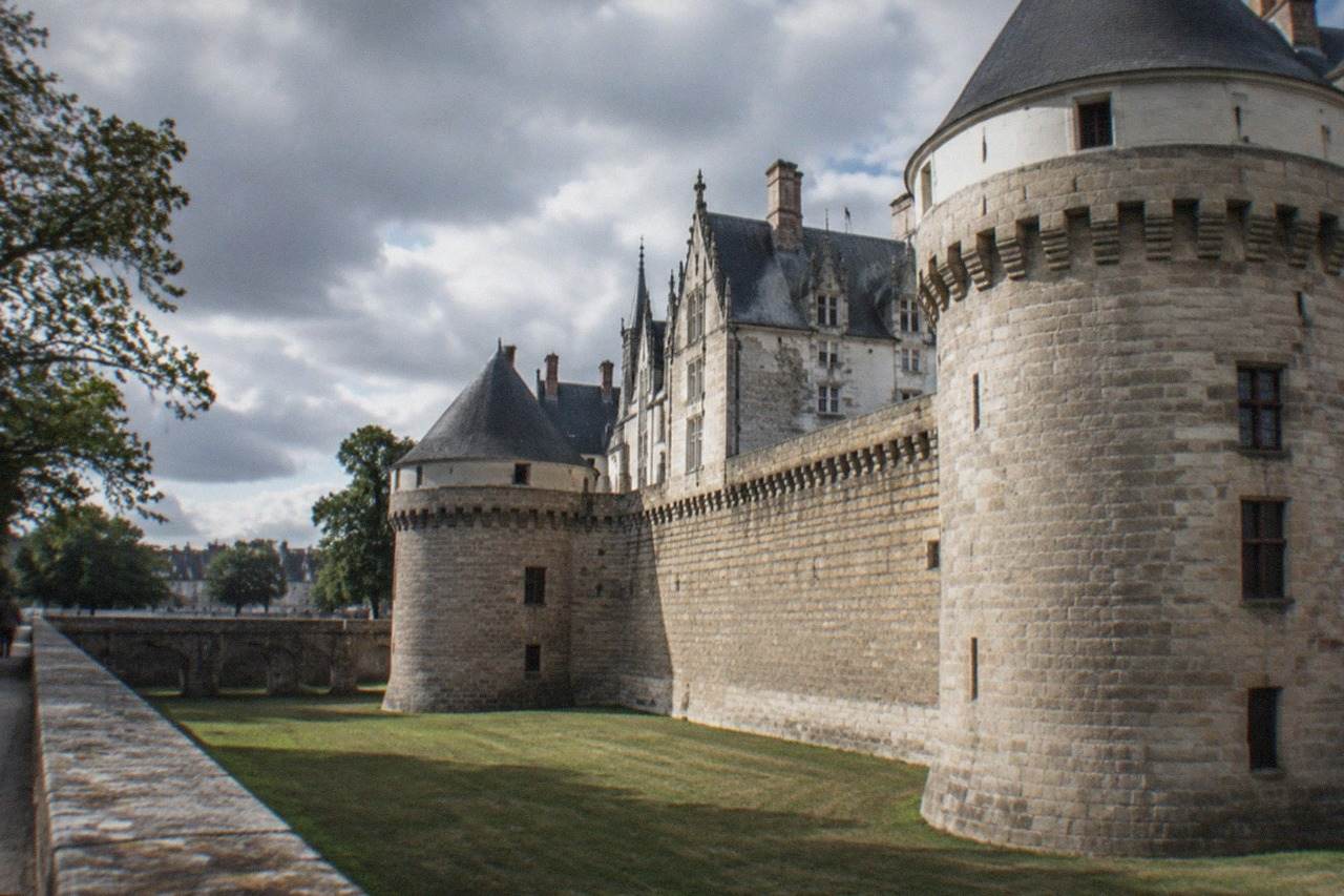 The stone ramparts and round towers of the Château des ducs de Bretagne in Nantes rising above the dry moat on a bright afternoon