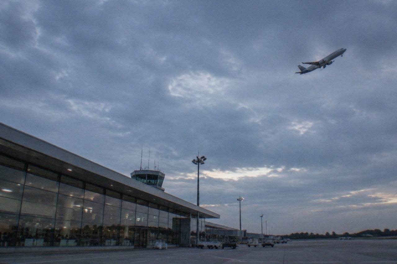 A passenger aircraft climbing above the runway of a regional French airport in late afternoon light