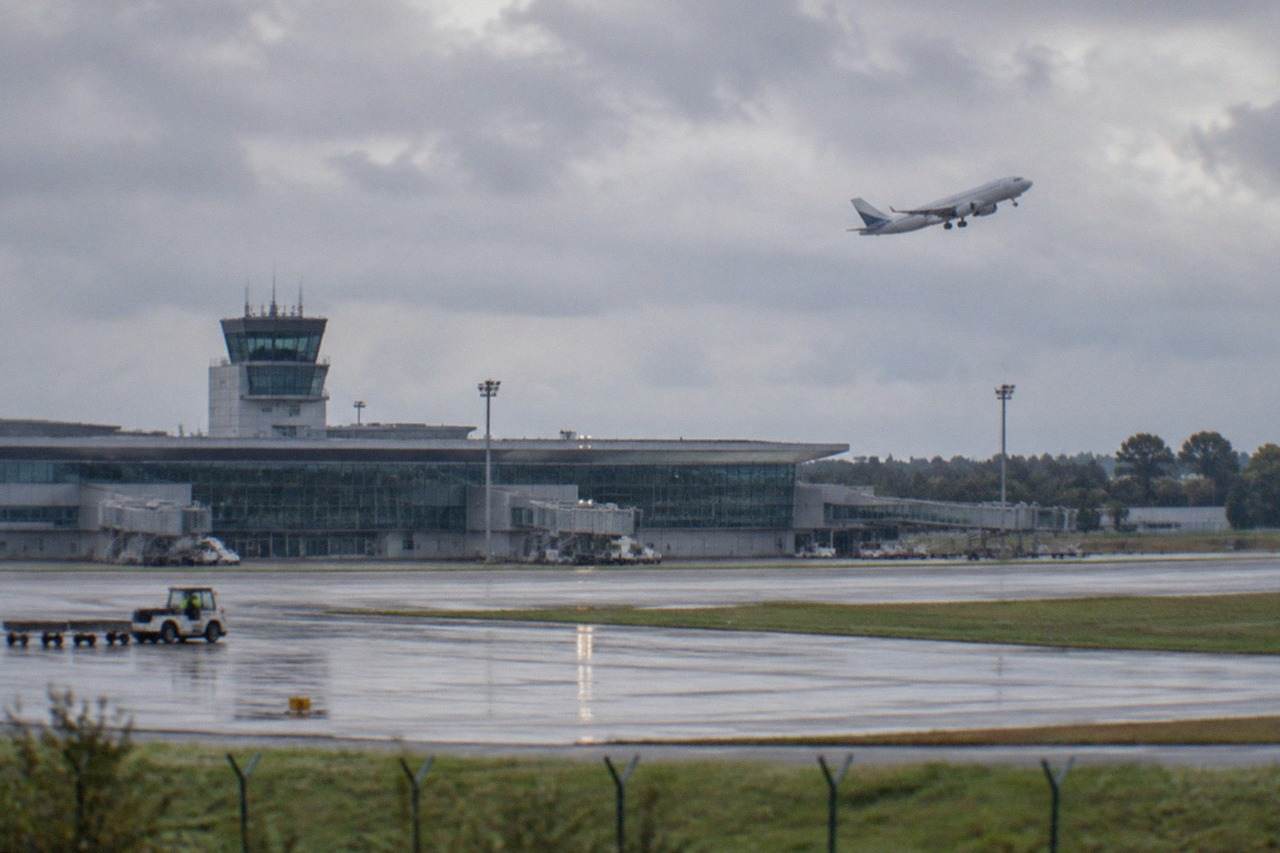 A passenger aircraft climbing over the runway at Nantes Atlantique airport on a bright afternoon