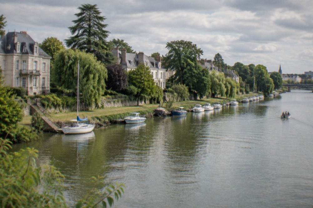 A sunny summer afternoon along the Erdre river in Nantes with boats moored near the bank