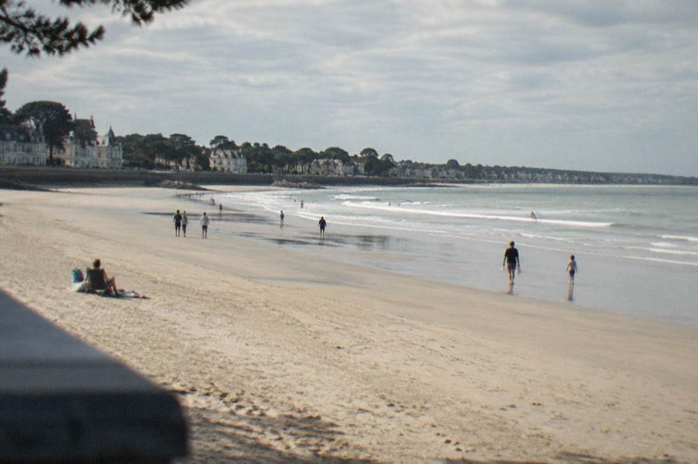 A sandy Atlantic beach at low tide near La Baule, with gentle waves and a wide stretch of sand under a clear sky