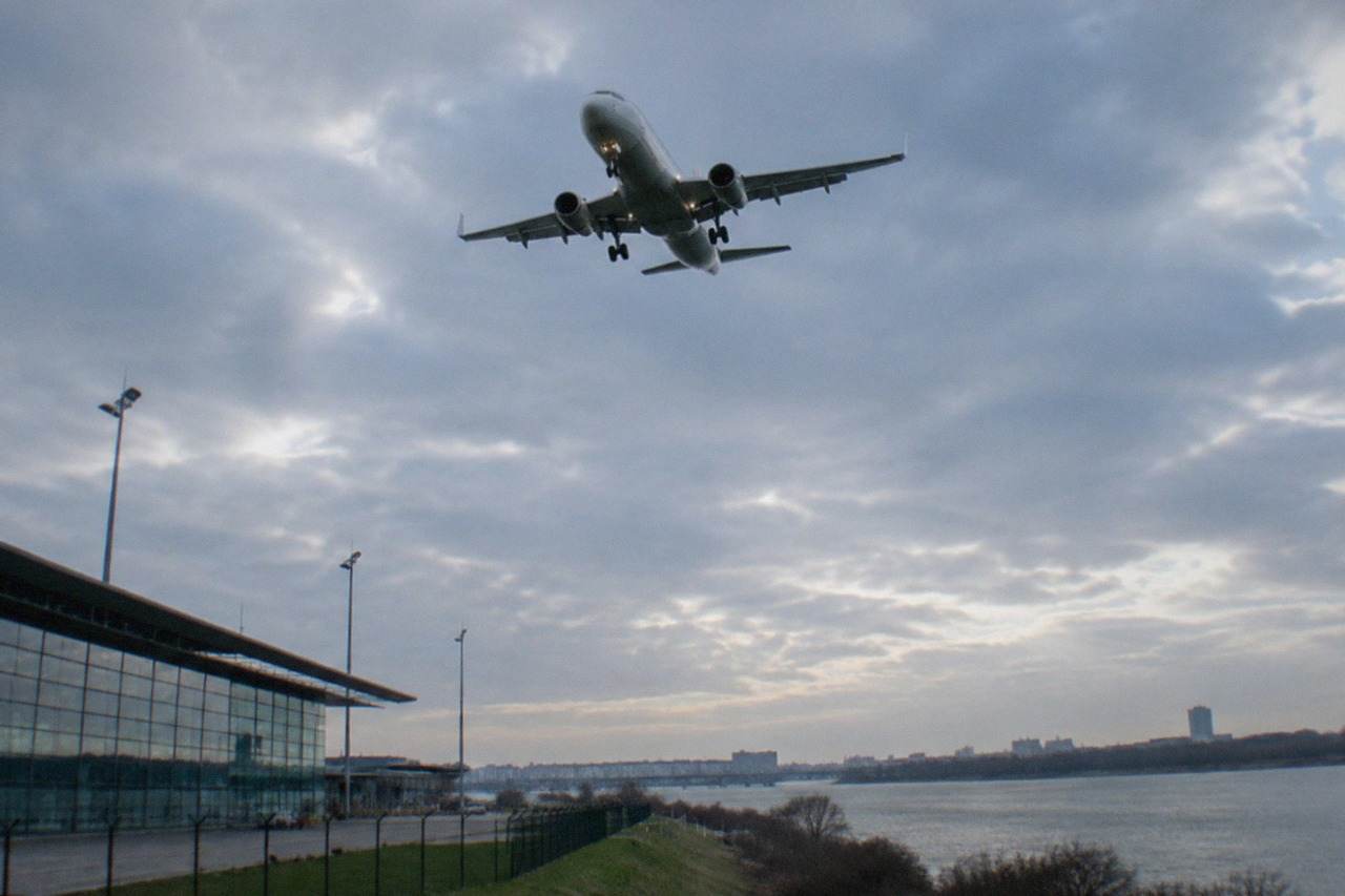 A short-haul passenger aircraft descending over the Loire river towards Nantes Atlantique airport on a clear afternoon