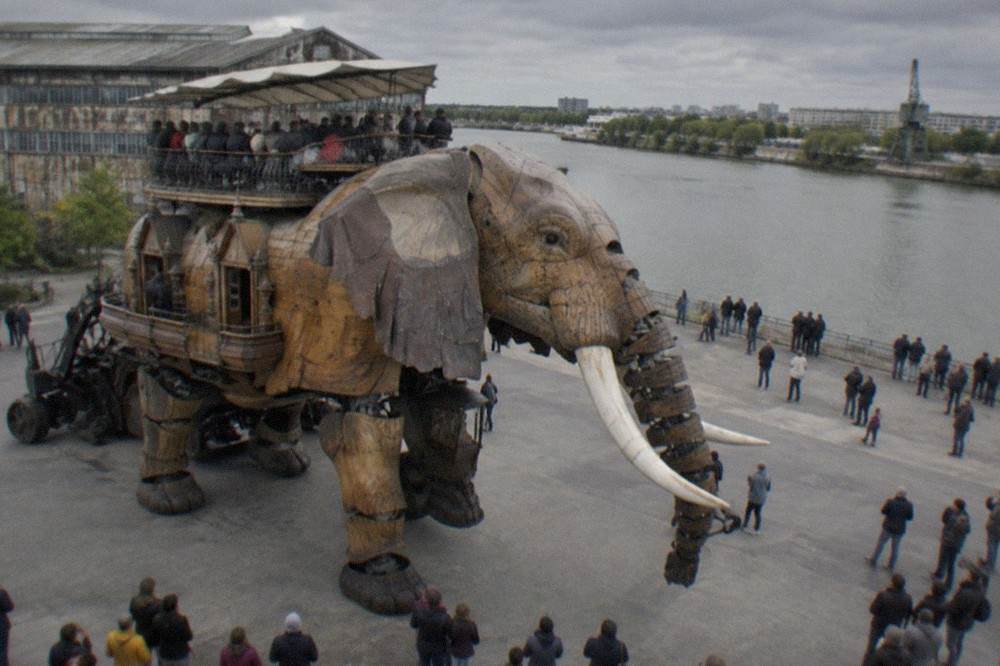Passengers seated on the back of the twelve-metre mechanical elephant above the Île de Nantes