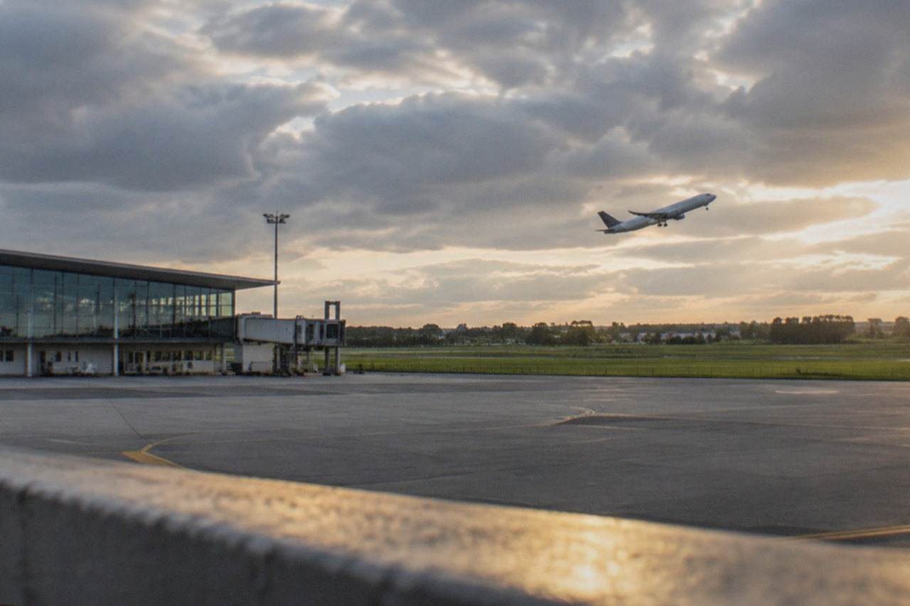 A passenger aircraft climbing away from Nantes Atlantique Airport above green fields on the edge of the city