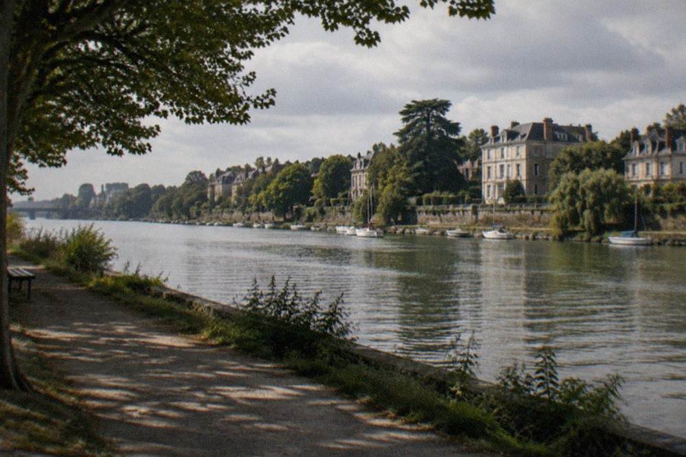 The tree-lined Erdre river in Nantes seen from a riverside path near the Île de Versailles
