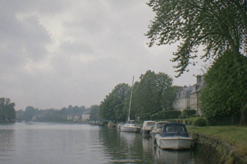 Boats moored on the Erdre river in Nantes with trees along the bank