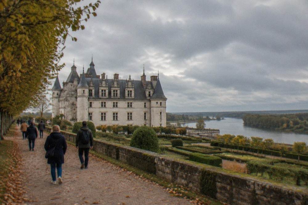 Visitors walking a tree-lined path toward a Loire Valley château on a bright autumn day