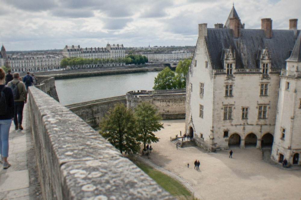 Visitors walking the stone ramparts of the Nantes château with the courtyard below