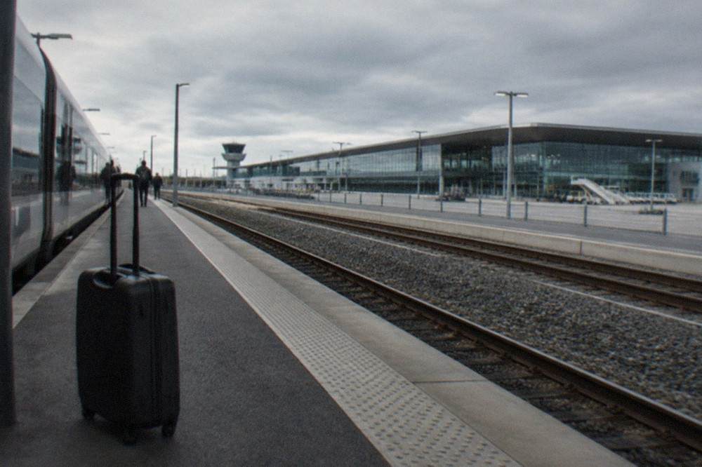 A travellers suitcase standing on a station platform beside a waiting high-speed train