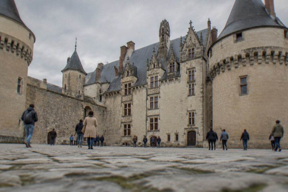 Visitors walking through the stone courtyard of the Château des ducs de Bretagne on a bright afternoon