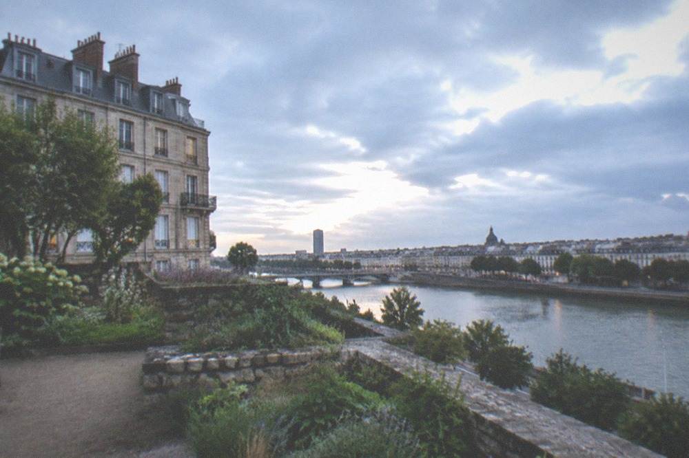 A terrace garden with stone retaining walls and plants overlooking a river valley in Nantes