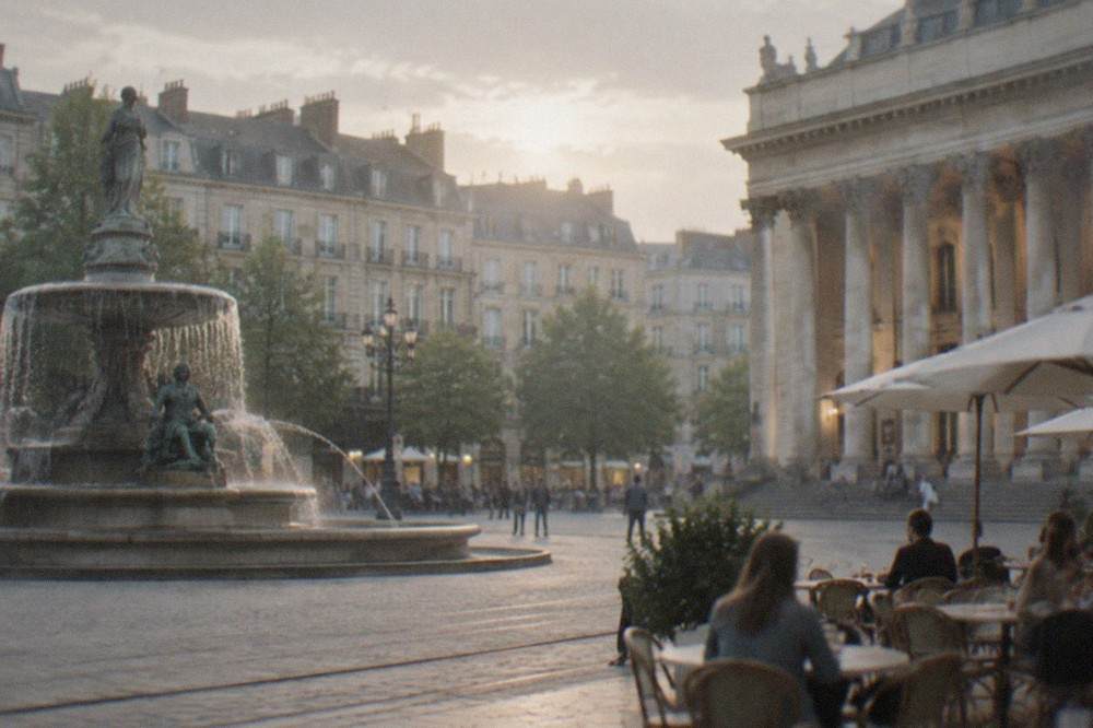 Evening light on a fountain and theatre columns in a Nantes square with people at café tables