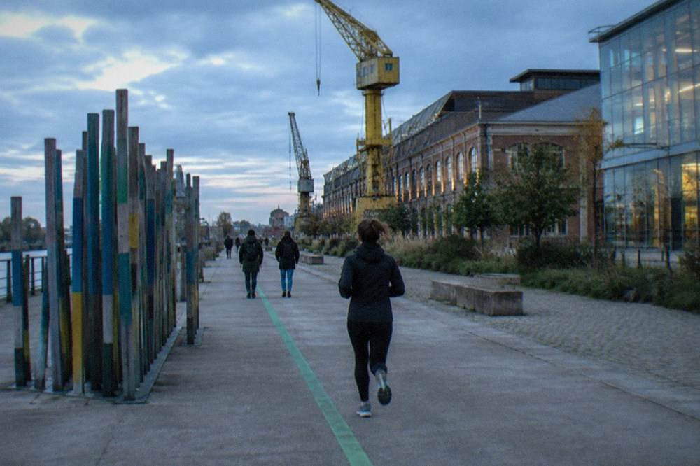 Visitors following the painted green line past a contemporary art installation on the Île de Nantes