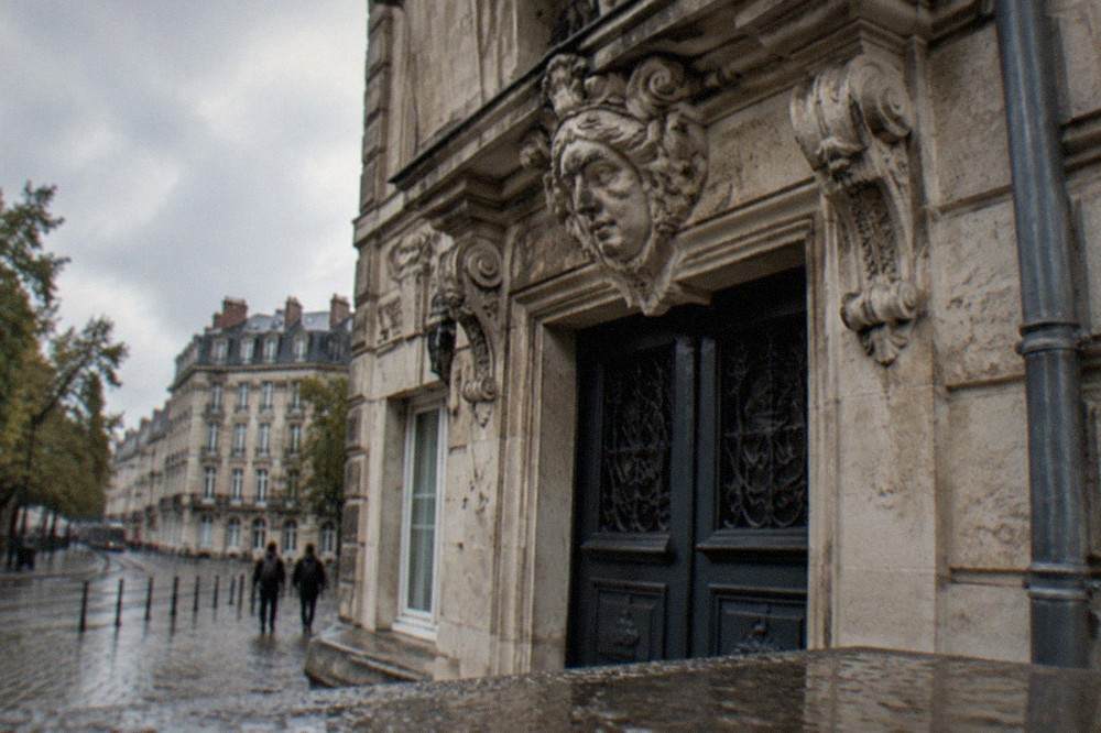 A close view of an ornate stone facade with a carved face ornament above a doorway in Nantes