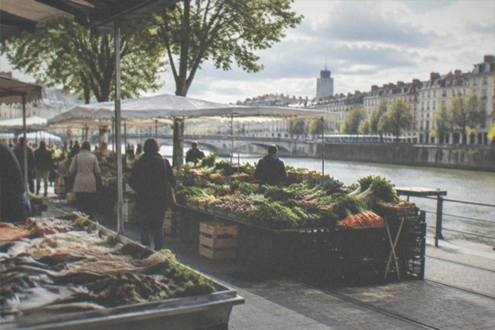 A busy French market stall with fresh fish and vegetables under morning light in Nantes