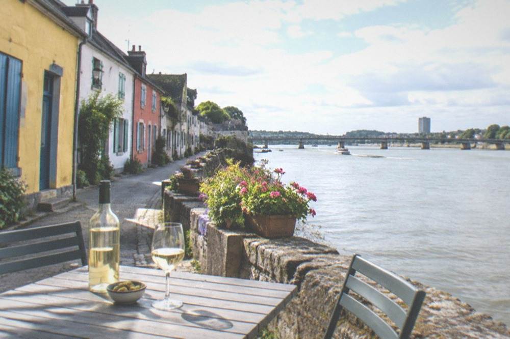 A table with a bottle of white wine and glasses beside the river at Trentemoult