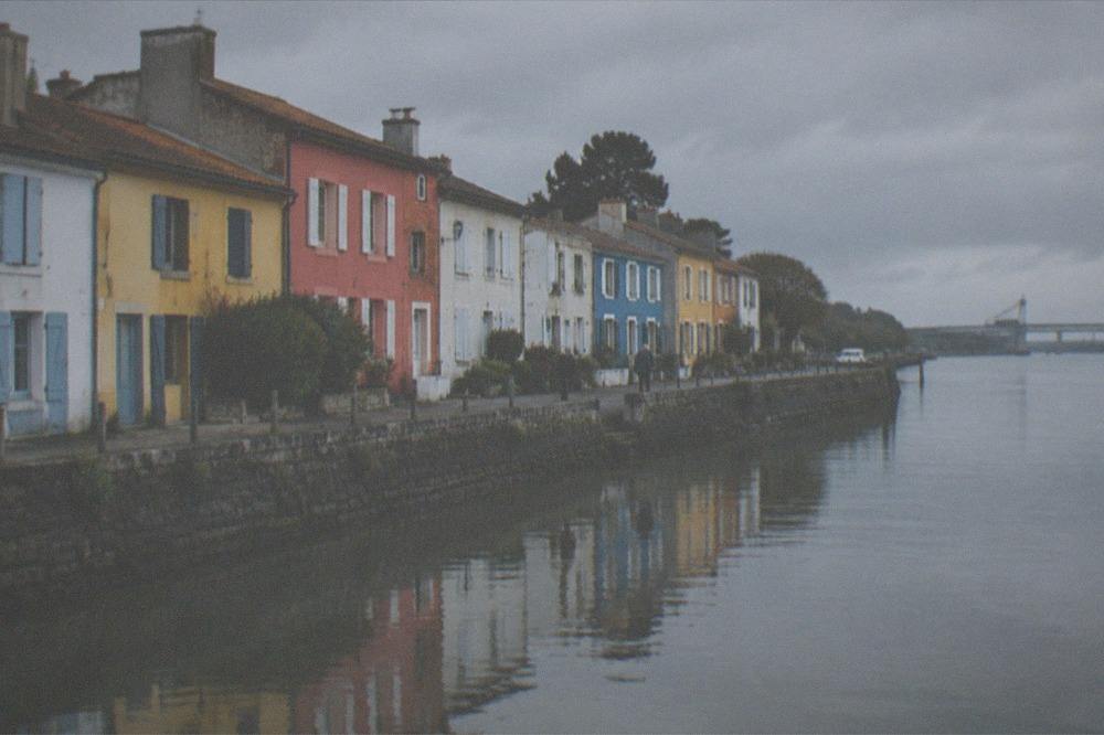 Morning light on the coloured house fronts of Trentemoult reflected in the calm water of the Loire