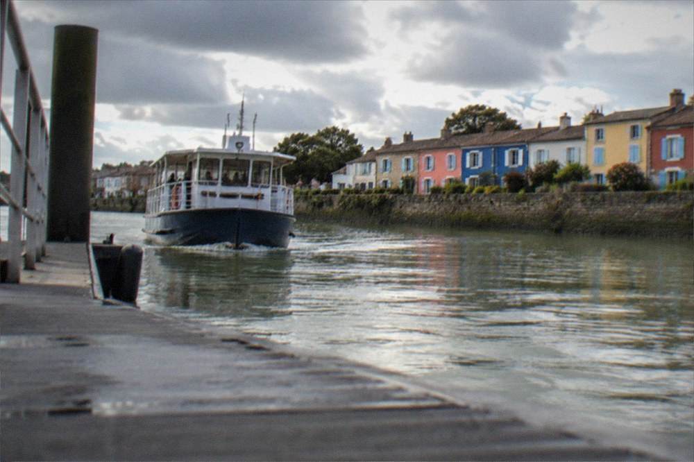 A river shuttle boat approaching the pontoon at Trentemoult with coloured houses behind