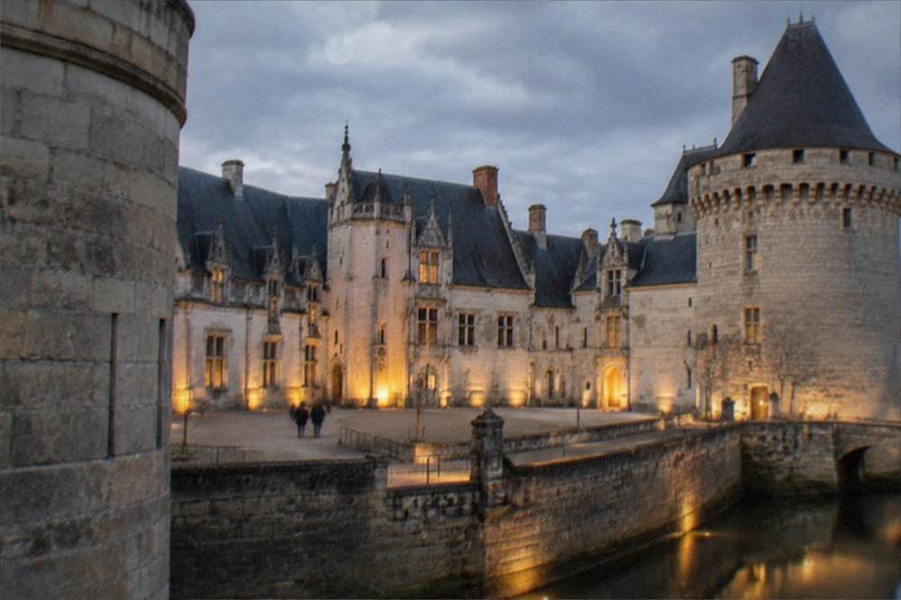 A floodlit castle courtyard with ramparts and a stone keep at dusk
