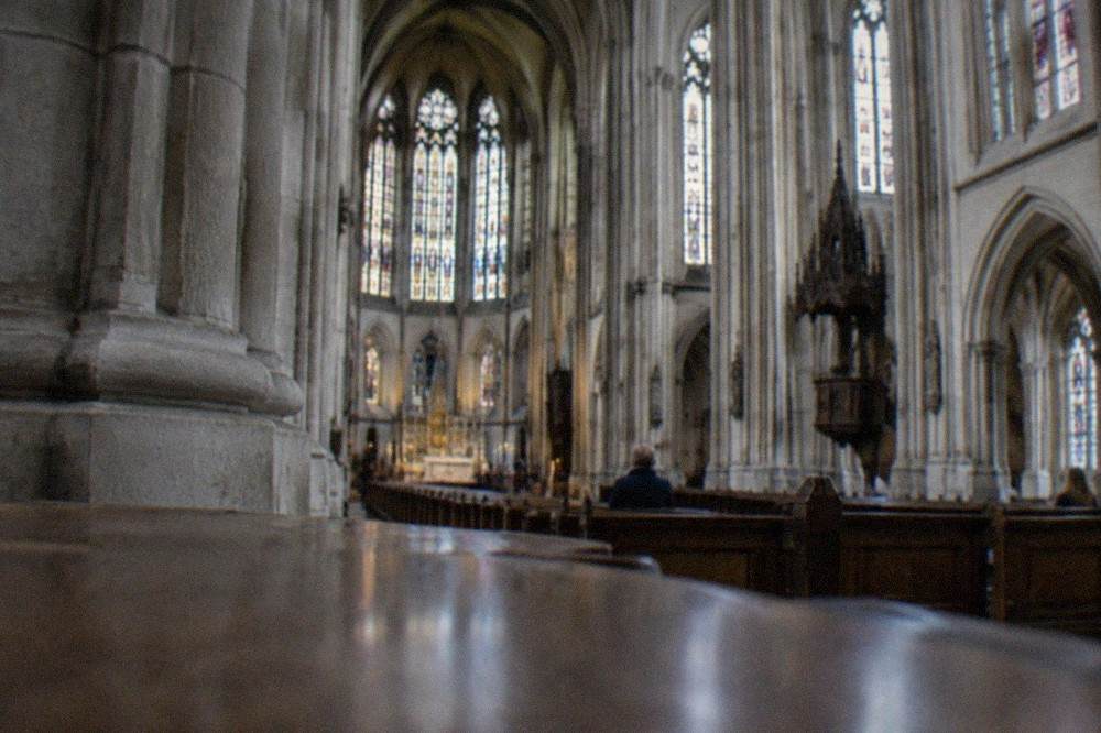 Interior of a Gothic revival church in Nantes with tall stone pillars and stained glass windows