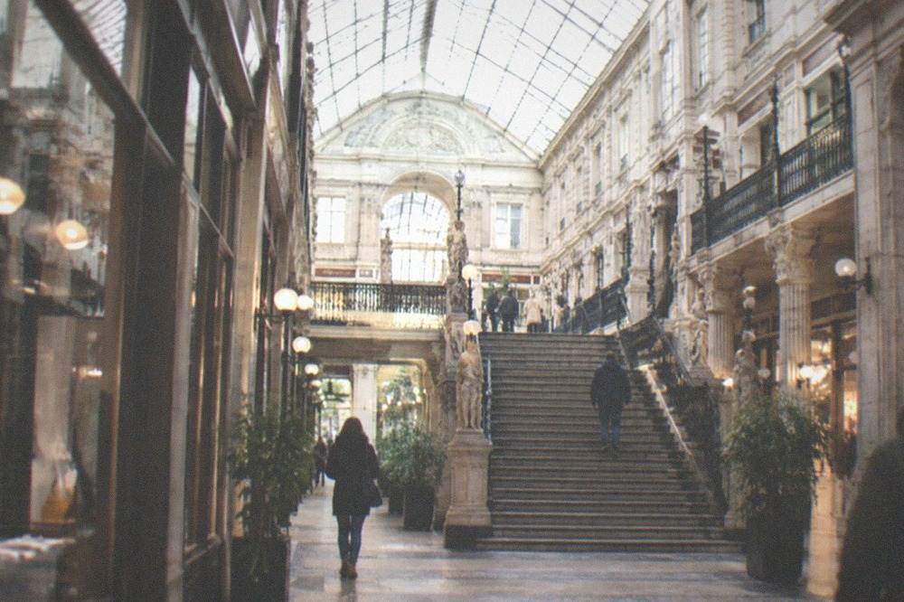 Illuminated 19th-century covered shopping gallery with a grand staircase in Nantes