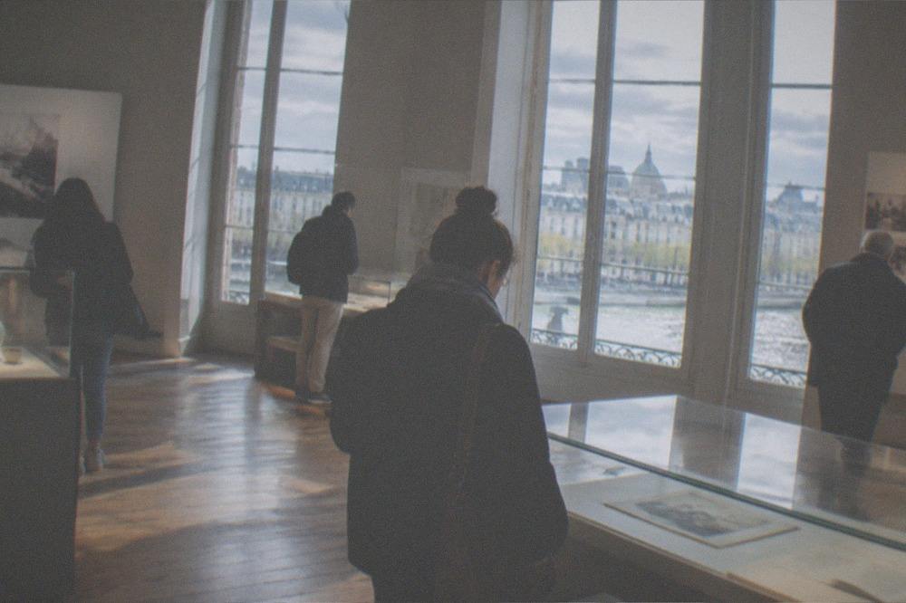 Visitors reading displays inside a museum gallery with tall windows in Nantes