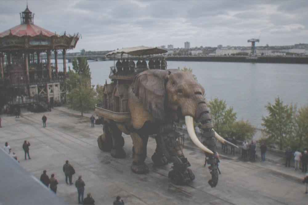 The walking mechanical elephant moving along the quay beside the carousel on the Île de Nantes