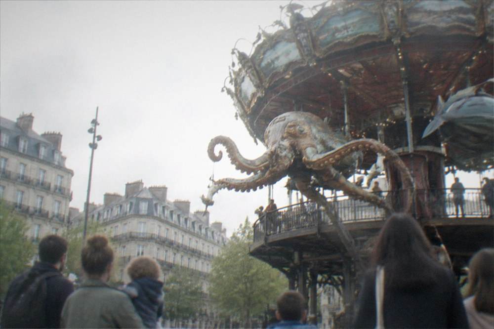 Children and parents watching a mechanical sea creature move on a carousel deck