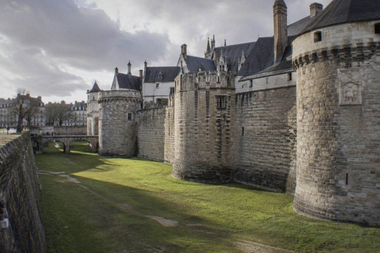 The Château des ducs de Bretagne with its massive round towers and moat garden in the foreground, seen from the Cours John Kennedy side on a sunny day.