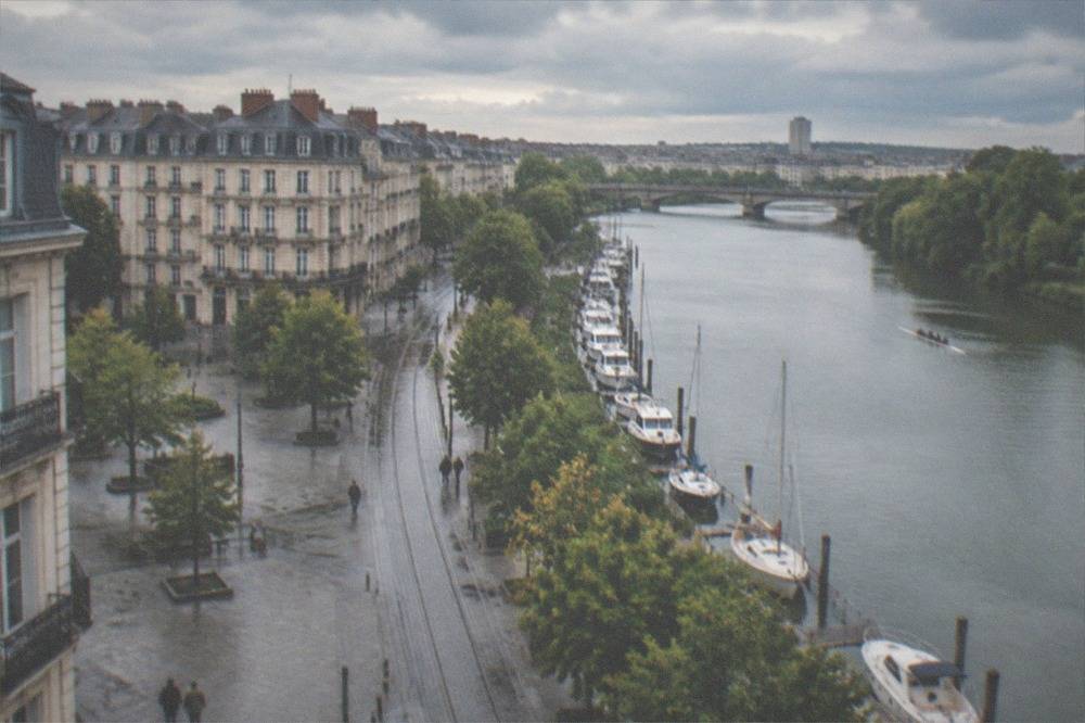 Rowing boats and small yachts moored along a leafy stretch of the Erdre