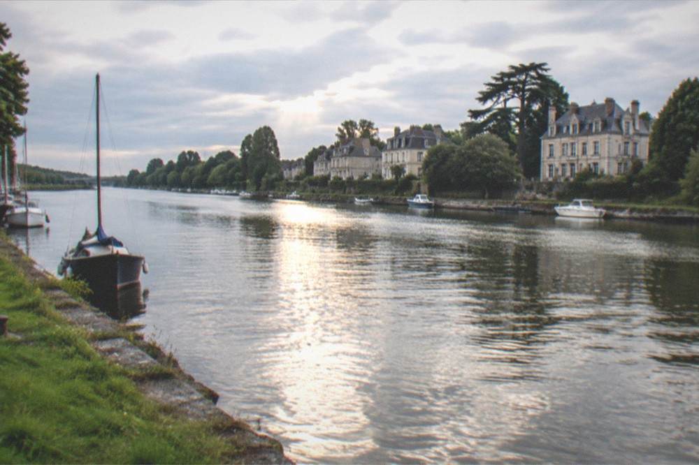 Sunset light reflecting on a river surface between stone quays and boats