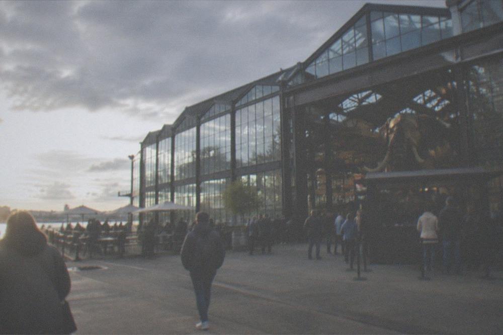 Ticket counter and visitors at the entrance of a mechanical attractions site in converted shipyard sheds