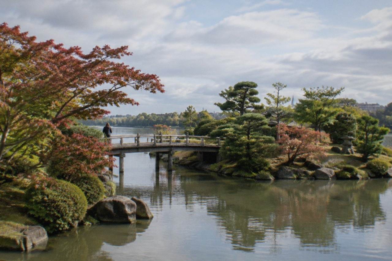 A quiet Japanese garden on a small river island with ponds, stones and pruned trees