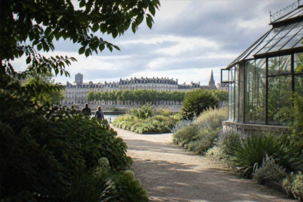 Path bordered by shrubs and a greenhouse in the Nantes botanical garden on a bright afternoon