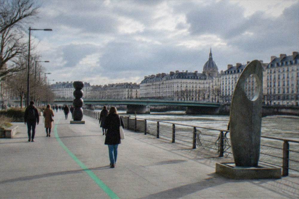 People walking along a green painted line marked on a Nantes pavement between public artworks
