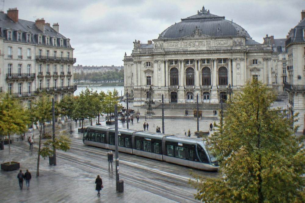 A city square in Nantes with a tram passing in front of an ornate opera house