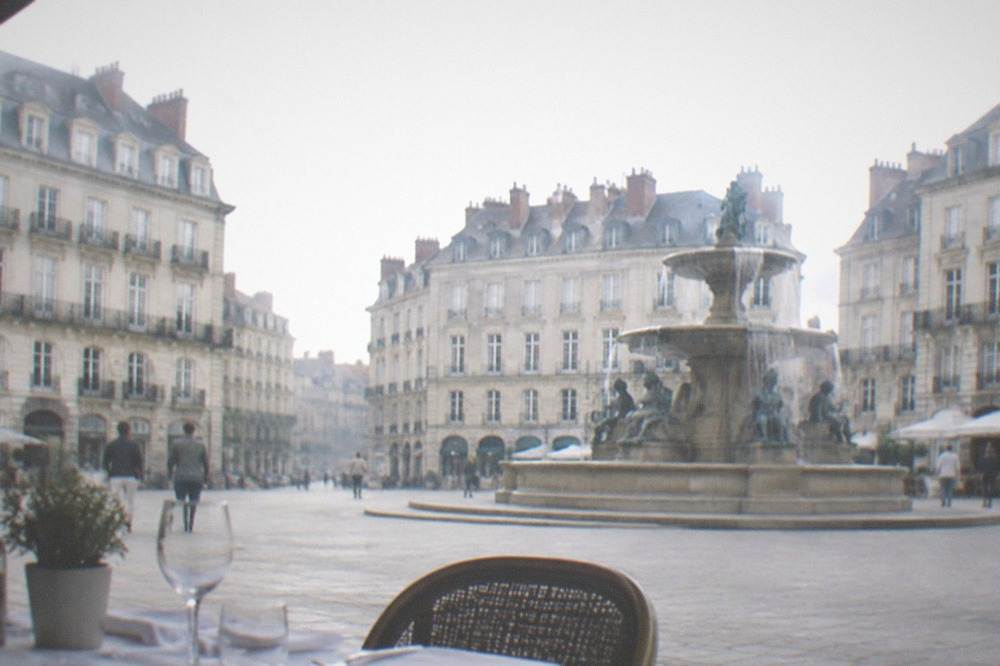 A table set with a white tablecloth, glassware and a menu in a traditional French brasserie