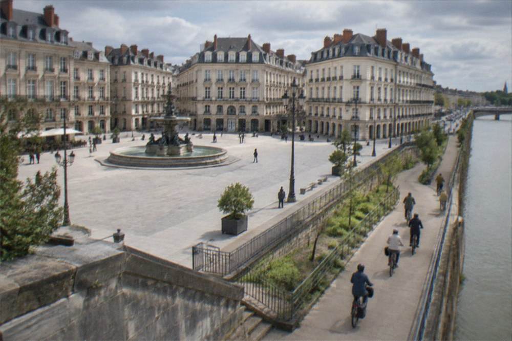 A group of cyclists on electric bikes riding along a riverside path in a French city