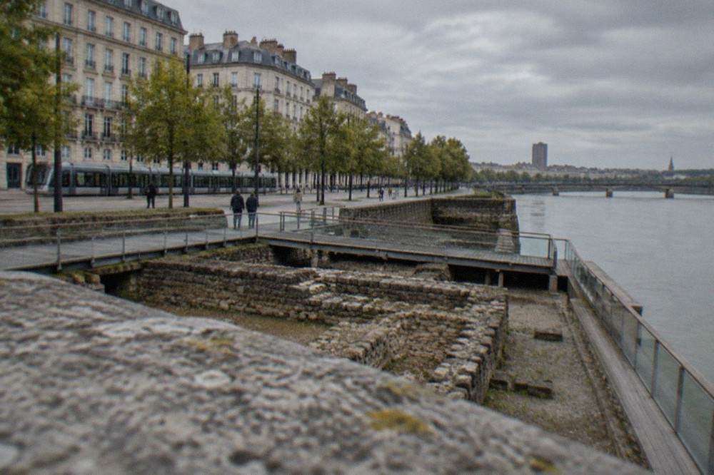 Excavated stone foundations of an ancient port displayed behind low glass and timber walkways