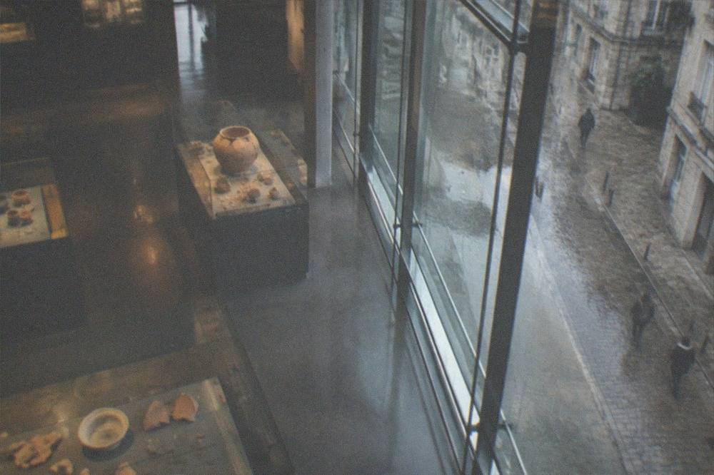 Display cases holding Roman-era pottery fragments and coins inside a dimly lit museum gallery