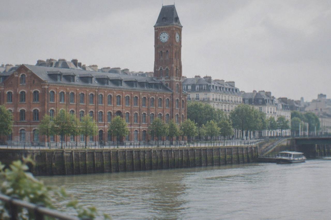 The brick facade and clock tower of a former biscuit factory beside a quay in Nantes