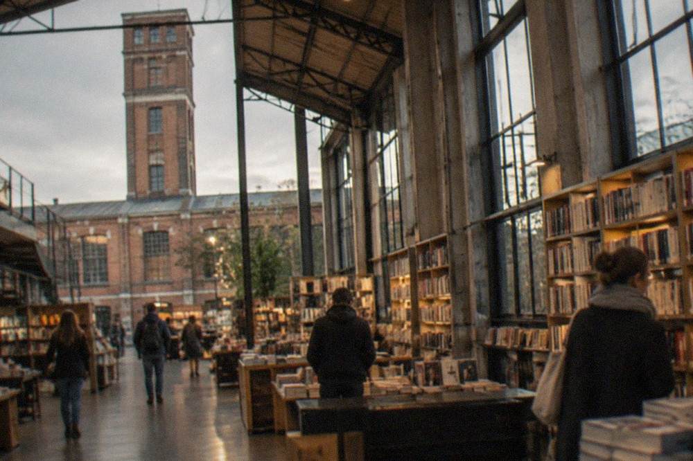 Visitors browsing bookshelves inside a converted industrial hall with high ceilings