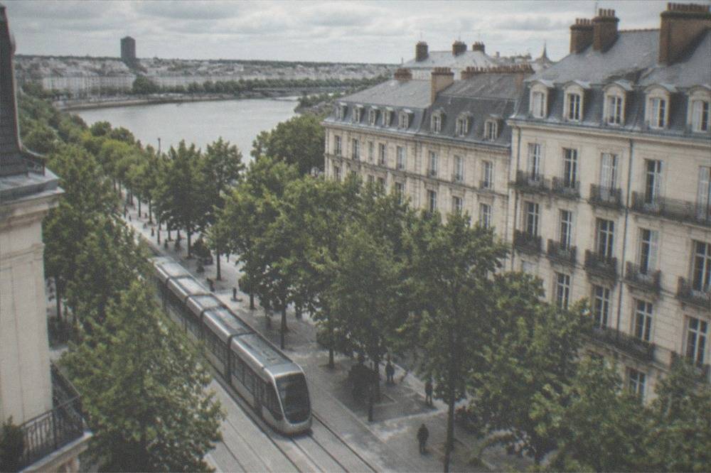 A Nantes tram passing along a tree-lined city street