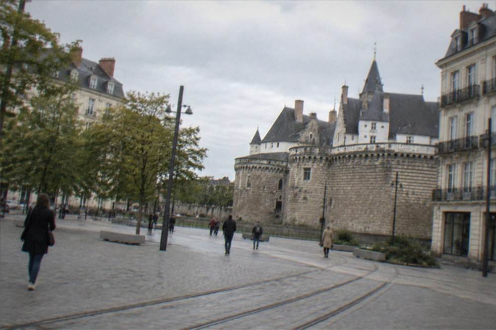 The stone ramparts of a castle in Nantes seen across an open square