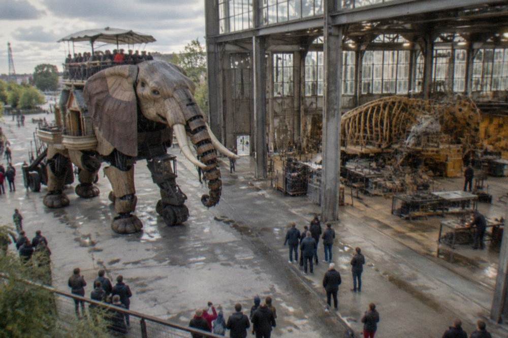 Artisans working on large mechanical machines inside the Galerie des Machines workshop hall