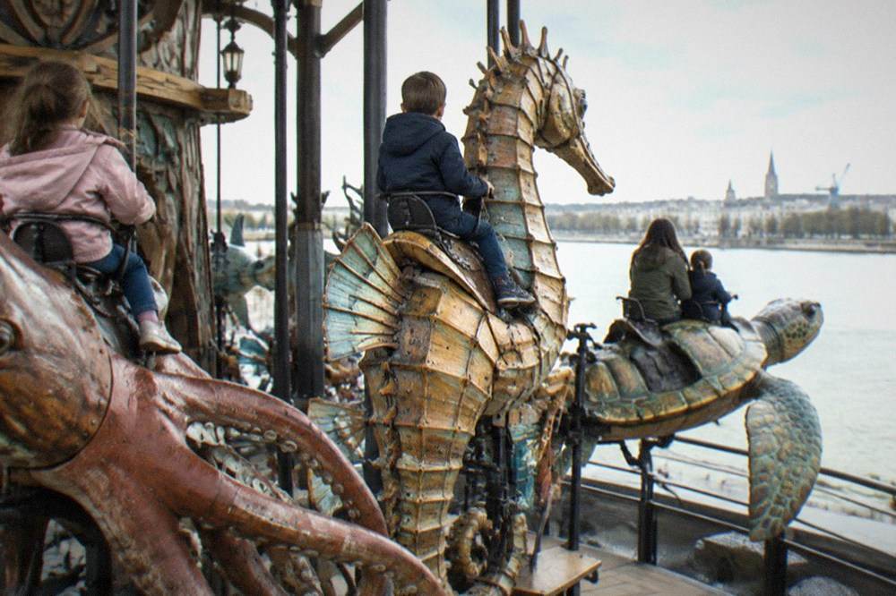 Families seated on giant mechanical sea creatures on the Carrousel des Mondes Marins