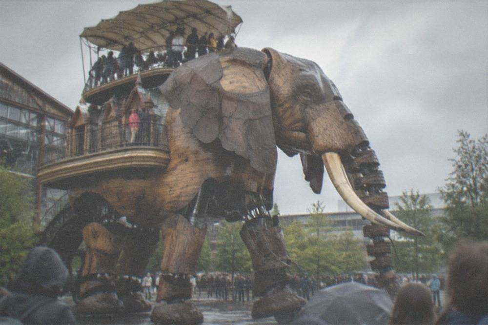 Visitors riding on the decorated back platform of the Grand Elephant mechanical elephant