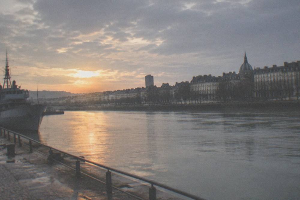 Sunset over the Loire in Nantes seen from a riverside quay with the outline of a grey ship and city rooftops