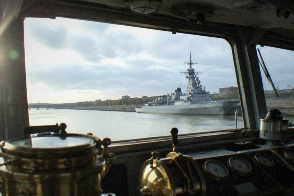 An old naval bridge interior with brass instruments, dials and windows looking out over a river