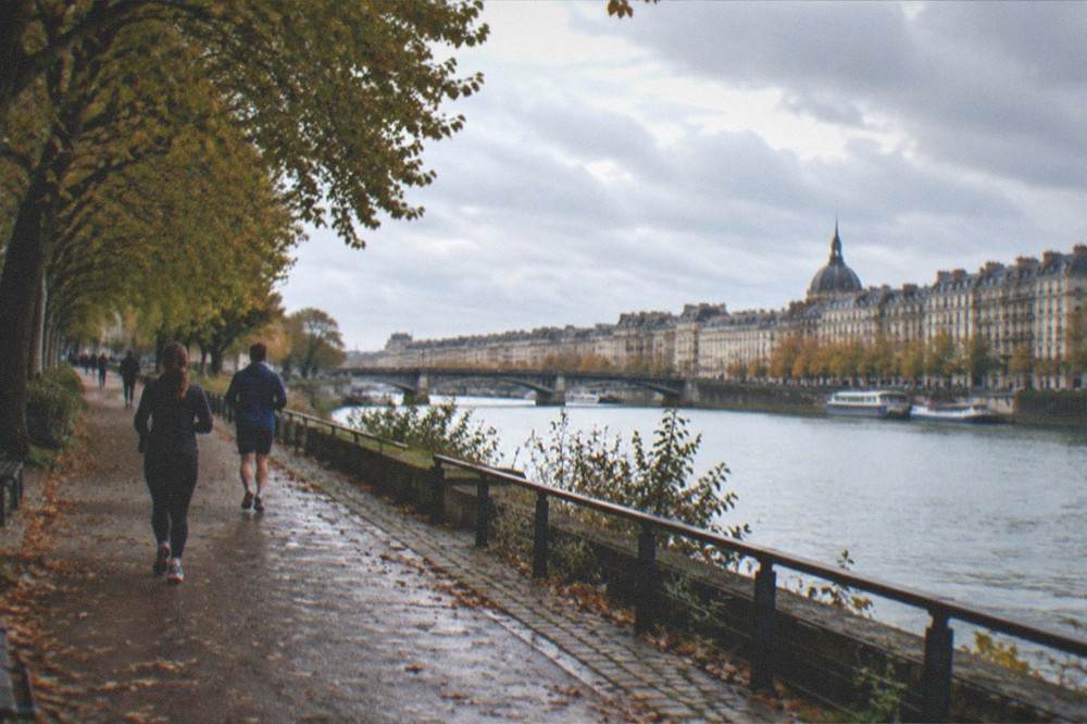 A riverside path along the Loire in Nantes on a quiet morning with joggers and trees in autumn light